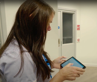 A nurse holding a mobile device and looking at the screen