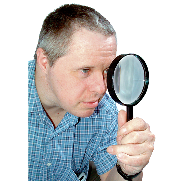 Man looking through a magnifying glass while wearing a blue checkered shirt.