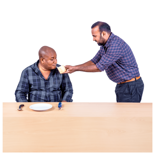 A person is helping another person by holding a cup