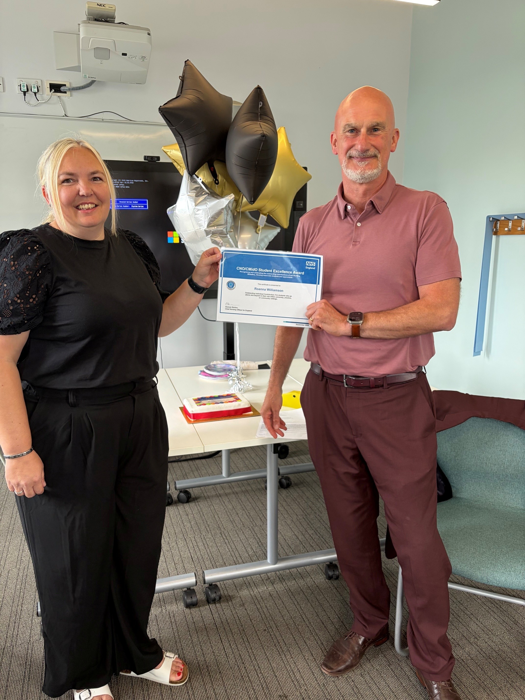 woman and man smiling. the man is handing the woman a certificate