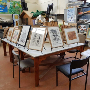 Several framed drawings on easels, on a tabletop in the Arts Project studio