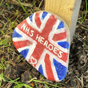 A stone lay on the grass, painted with a Union Flag and the words 'NHS Heroes'