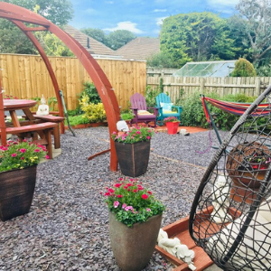 Kate's back garden, with gravel surface, picnic bench, garden chairs and potted plants.
