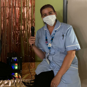 A staff member in uniform and a facemask holding the kareoke machine