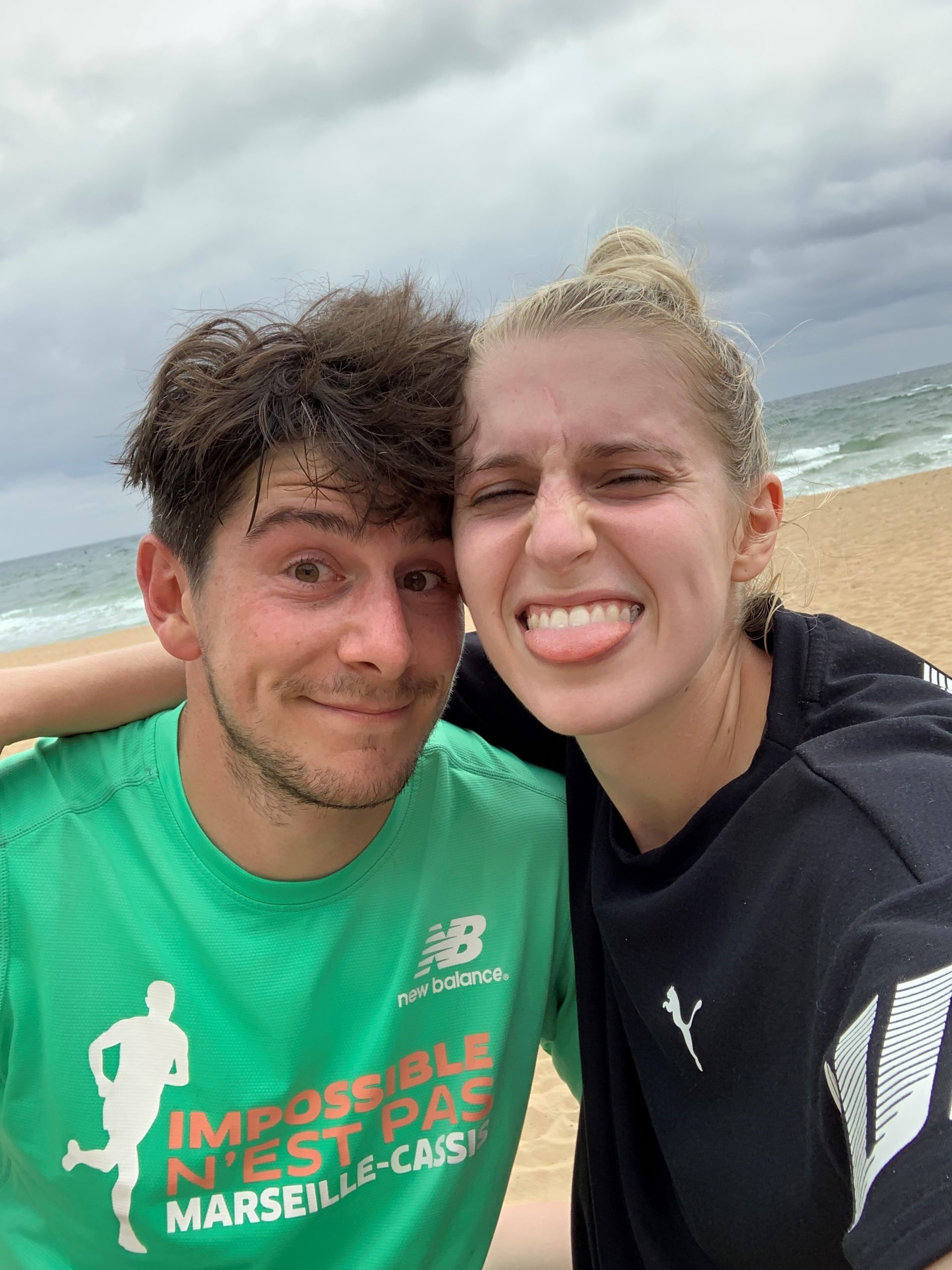 Abi and Alex taking a selfie together on a windswept beach