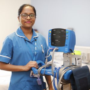 Nurse smiling holding hospital equipment