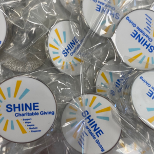 Photo of pin badge with SHINE charity logo