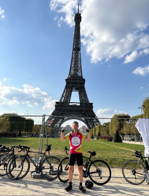 Paul Wales standing in front of the Eiffel Tower during his charity bike ride