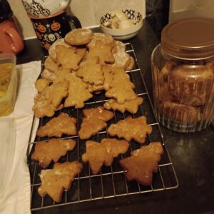A batch of christmas tree-shaped cookies cooling on a kitchen counter