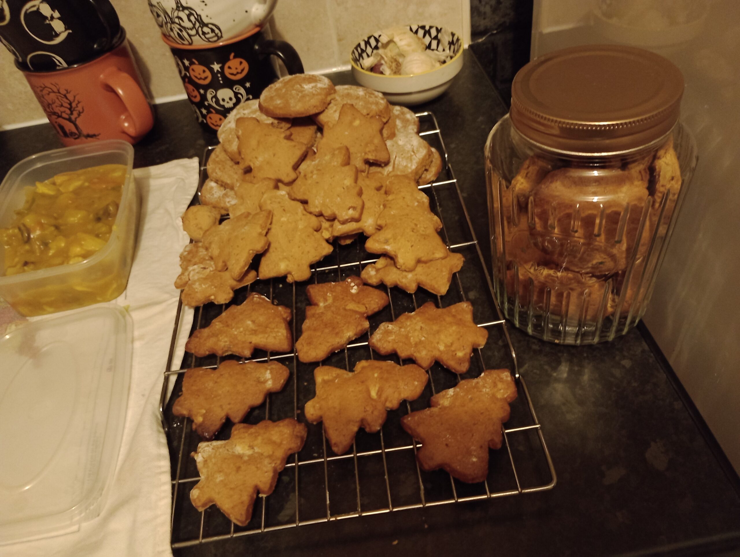 A batch of christmas tree-shaped cookies cooling on a kitchen counter